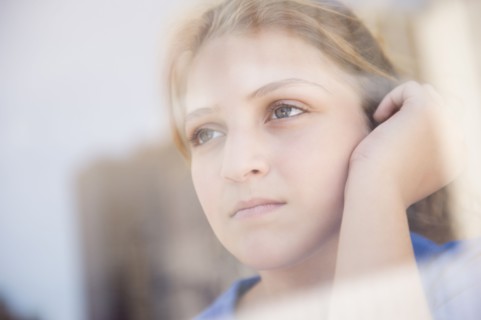 Portrait of teenage girl (12-13) looking through window