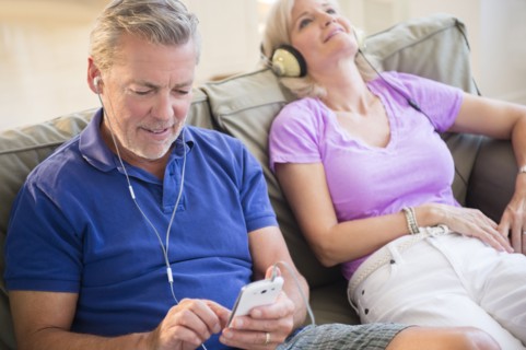 Portrait of couple sitting on sofa listening to music on headphones