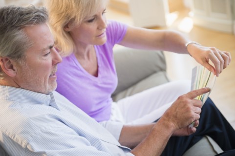 Portrait of couple sitting on sofa looking at sheet of paper