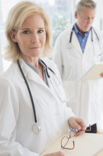 Portrait of female doctor holding clipboard and eyeglasses