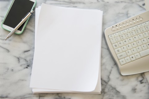 Studio shot of smart phone, sheets of paper, pen and computer keyboard