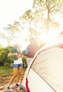 Couple standing next to tent in forest