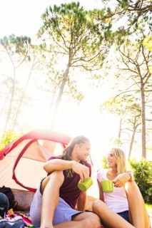 Couple sitting with coffee in front of tent