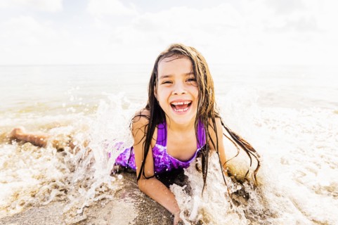 Portrait of girl (6-7) lying in sand on beach