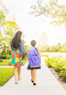 Rear view of girl (6-7) holding hands with her mom outdoors