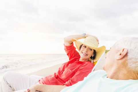 View of couple sitting in lounge chairs on beach