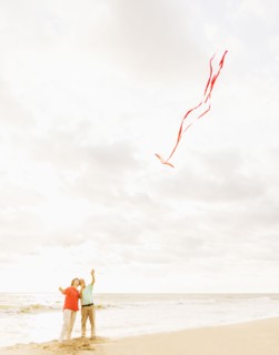 Couple flying kite together on beach