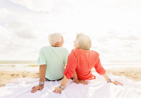 Rear view of couple looking at each other on beach at sunrise
