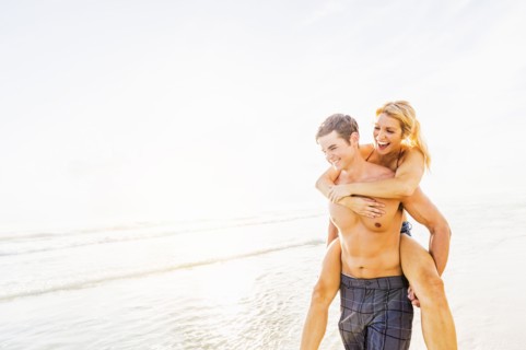 Boyfriend carrying girlfriend piggyback on beach