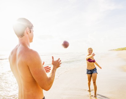 Young couple throwing football on beach