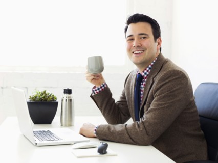 Portrait of businessman sitting in office and drinking coffee