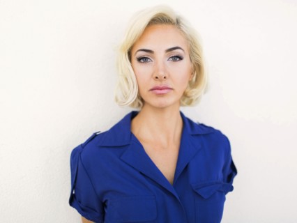 Woman in blue dress posing to camera against white background