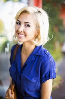 Woman with dyed hair and wearing blue dress looking at camera