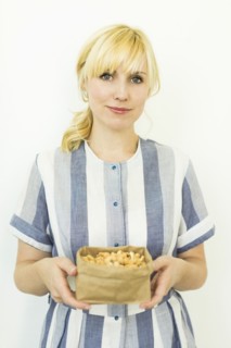 Studio shot of woman holding cashews in paper bag