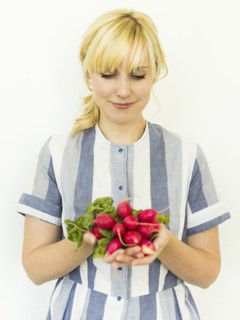 Studio shot of woman holding bunch of fresh radishes