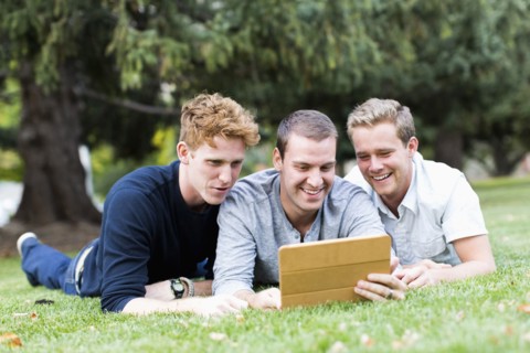 Portrait of young men using digital tablet in park