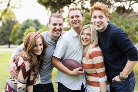 Portrait of friends with football in park