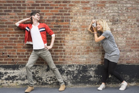 Woman taking pictures of man.