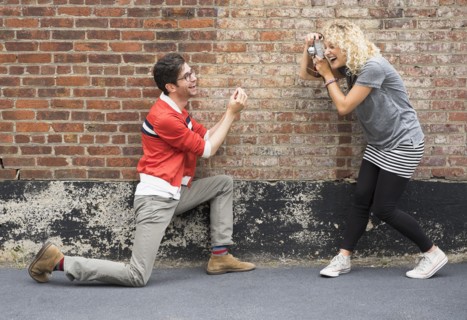 Woman taking pictures of man.