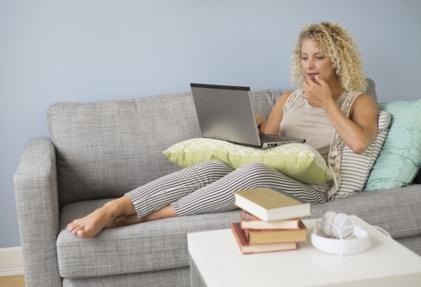Woman sitting on sofa using laptop.