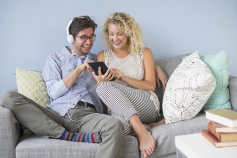 Couple sitting on sofa listening to music.