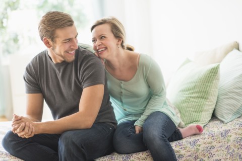 Smiling couple sitting on bed.