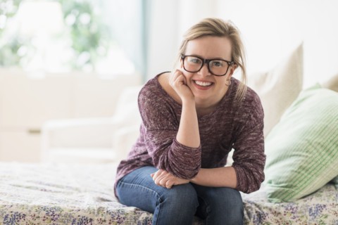 Portrait of smiling young woman sitting on bed.