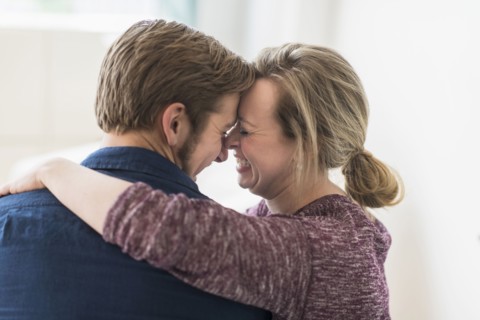 Close-up of smiling couple embracing.