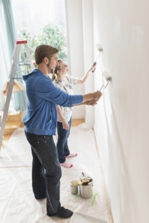 Smiling couple painting wall.
