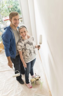 Portrait of smiling couple painting wall.