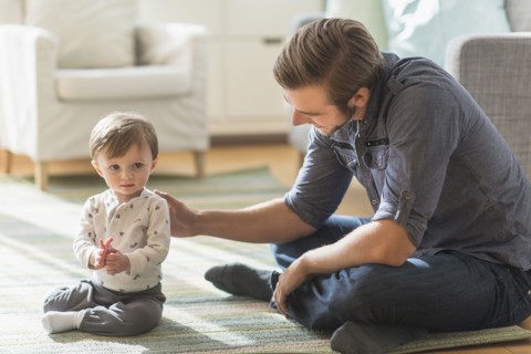 Father sitting on floor with little son (2-3 years).