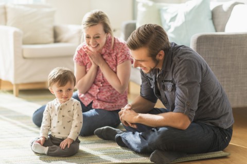 Happy parents sitting with little son (2-3 years) on floor.