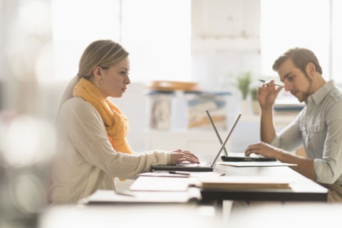 Young man and woman working at desk in office.