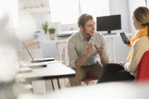 Young man and woman discussing at desk in office.