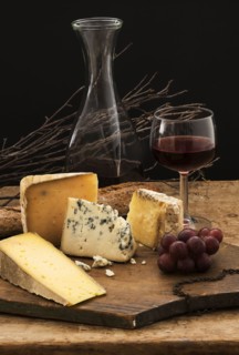 Still life with cheese and red wine on wooden table, studio shot.