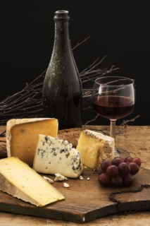 Still life with cheese and red wine on wooden table, studio shot.