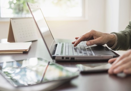 Close up of man's hands using laptop at desk.