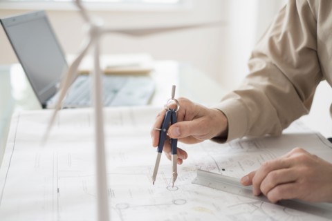 Close up of man's hands using compass while drawing plans.