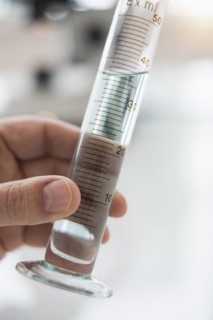 Close up of man's hand holding test tube with liquid.