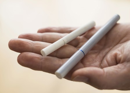 Close up of man's hand holding cigarette and e-cigarette.