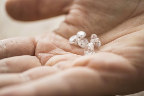 Close up of man's hand holding diamonds.