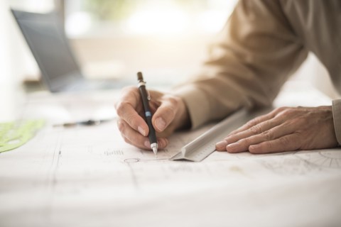 Close up of architect's hands drawing on blueprint.