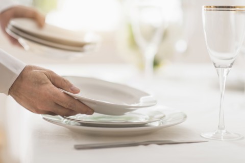 Close up of man's hand setting place in restaurant.
