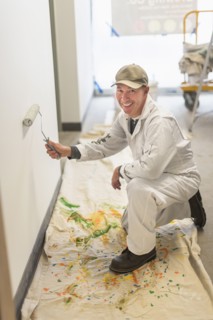 Portrait of smiling manual worker painting wall.