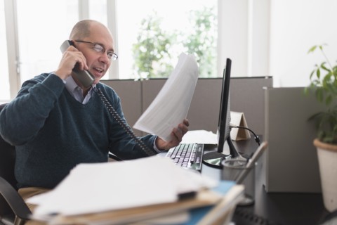 Mature businessman using landline phone in office.