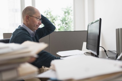 Surprised mature businessman looking at computer monitor .