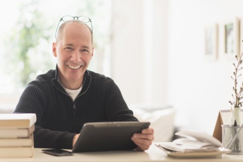 Portrait of smiling mature man working in home office .