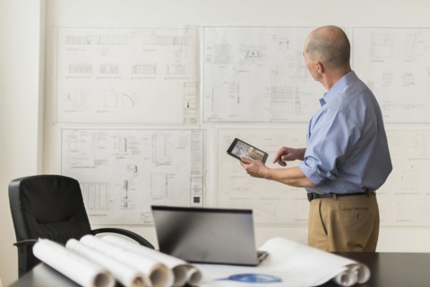 Mature architect looking at blueprints in office.