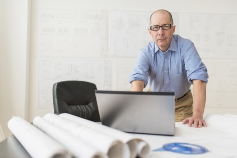 Portrait of mature architect using laptop in office.