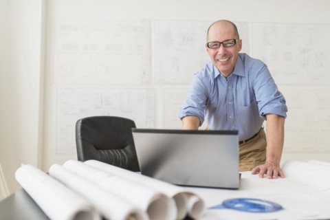 Portrait of smiling mature architect using laptop in office.